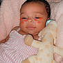 Amani is registered to the contest to win money with this photo: baby, infant, plush_toy, giraffe, blanket, pink, striped_clothing, cute, face, child, soft_toy, sleepy, resting, indoors, cozy, smiling, person, toddler, cheeks, adorable
