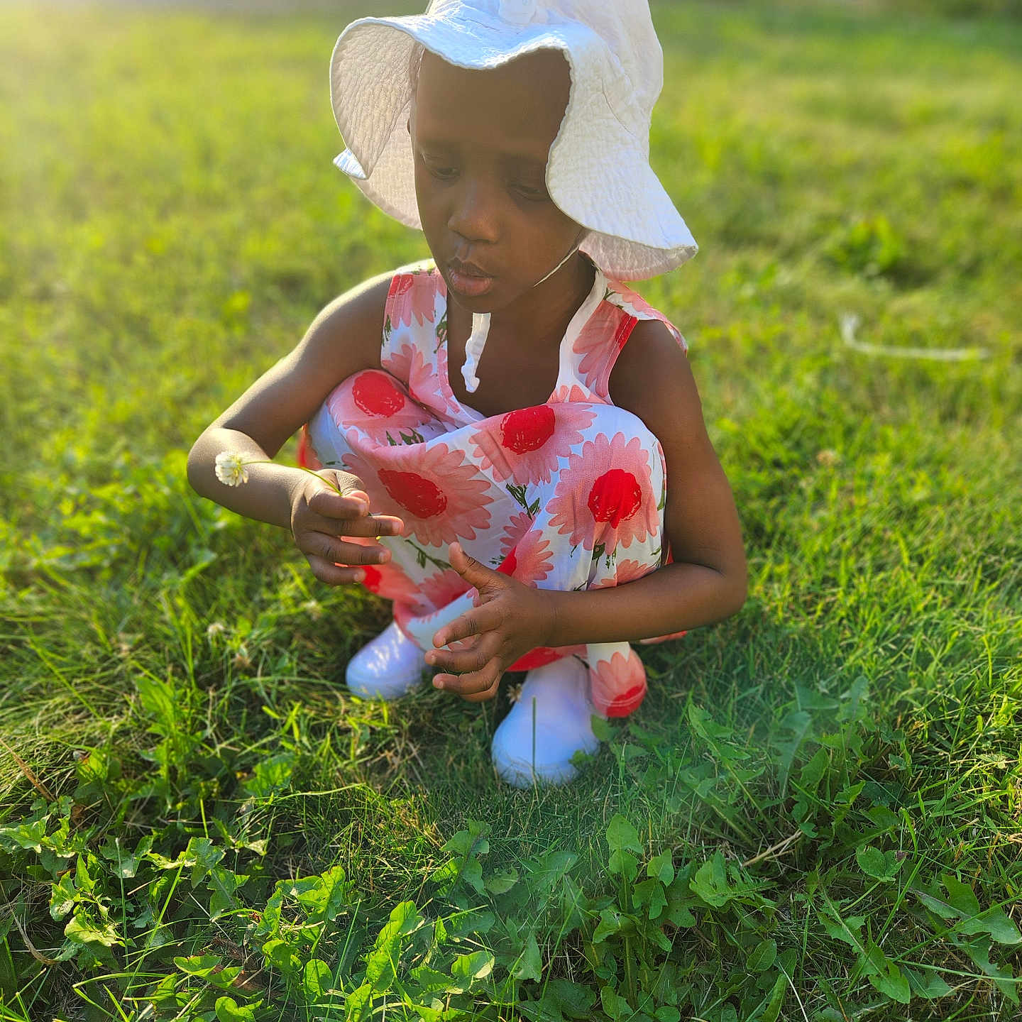 Quahniyha is registered to the contest to win money with this photo: child, clothing, dress, face, female, footwear, girl, grass, hat, head, lawn, outdoors, person, photography, plant, portrait, shoe, sitting, summer, sunhat