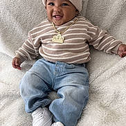 Kaleo joined the competition — help win amazing prizes! baby, child, smiling, portrait, indoor, blanket, beanie, sweater, striped_clothing, jeans, sneakers, necklace, fashion, sitting, lying_down, happy, face, infant, cozy, furry_blanket