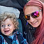 Logan is registered to the contest to win money with this photo: toddler, child, woman, smile, curly_hair, plaid_shirt, stroller, seatbelt, sunglasses, red_hair, earring, outdoor, happy, face, portrait, people, fashion, accessory, daylight, closeup