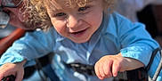 Logan joined the competition — help win amazing prizes! child, toddler, curly_hair, smiling, shopping_cart, blue_shirt, adult, glasses, outdoor, sunlight, happy, person, playful, metal, hand, face, jeans, daylight, closeup, family