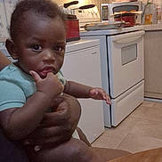 Legacy is registered to the contest to win money with this photo: baby, child, kitchen, stove, microwave, hand, thumb, person, indoor, furniture, table, appliance, curious, holding, skin, face, sitting, clothing, adult_hand, floor