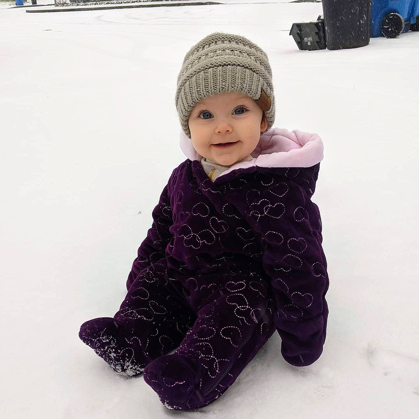 Colette is registered to the contest to win money with this photo: baby_toddler_clothing, cap, cheek, child, freezing, fur, head, headwear, hood, jacket, joy, knit_cap, pattern, person, playing_in_the_snow, recreation, sitting, sleeve, smile, snow