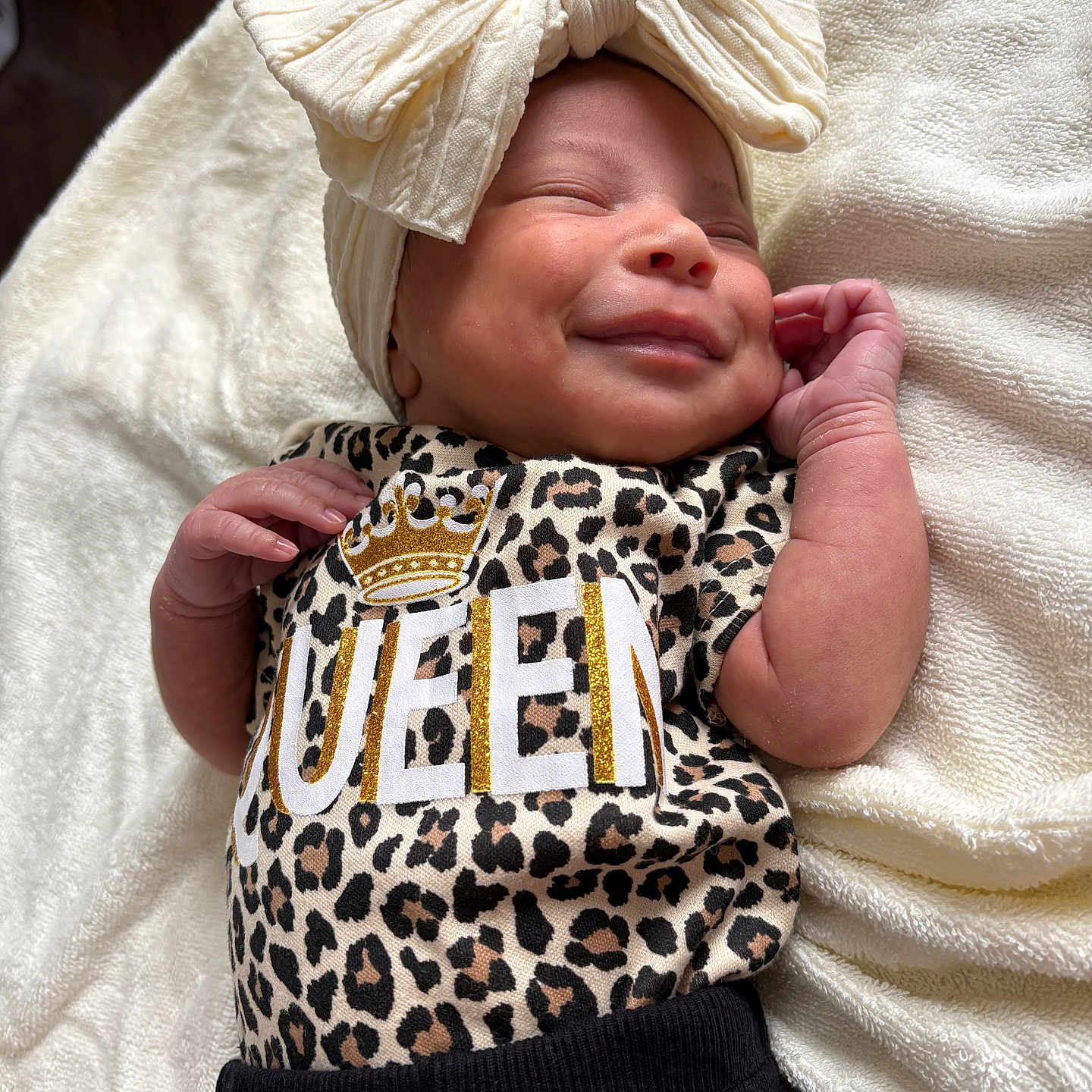 Miloni is registered to the contest to win money with this photo: baby, newborn, smiling, headband, bow, leopard_print, clothing, blanket, infant, cute, sleepy, soft_texture, closeup, portrait, resting, small_hands, cozy, happy, child, adorable