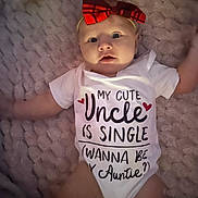 Evelynn is registered to the contest to win money with this photo: baby, infant, child, portrait, lying_down, blanket, red_bow, headband, onesie, clothing, text_on_clothing, wide_eyed, indoor, cozy, close_up, face, arms, legs, smiling, cute