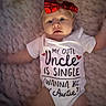baby, infant, child, portrait, lying_down, blanket, red_bow, headband, onesie, clothing, text_on_clothing, wide_eyed, indoor, cozy, close_up, face, arms, legs, smiling, cute