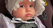 Everlee joined the competition — help win amazing prizes! baby, car_safety, car_seat, child, closeup, cute, expression, face, hand, indoors, infant, person, portrait, purple_clothing, safety_harness, seat_belt, sitting, transportation, white_bonnet, young_child