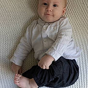 Neylan a rejoint le concours — aidez-le/la à gagner de superbes lots ! baby, barefoot, black_pants, blanket, child, cozy, curious_expression, cute, face, head, indoor, infant, light_skin, lying_down, person, portrait, small_feet, small_hands, smile, white_shirt