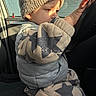 Neylan participe au concours pour gagner de l'argent avec cette photo : toddler, child, hat, knitted_hat, star_pattern, sweater, pants, car, steering_wheel, hand, face, profile, sunlight, window, seat, clothing, indoor, curious, warm_light, casual