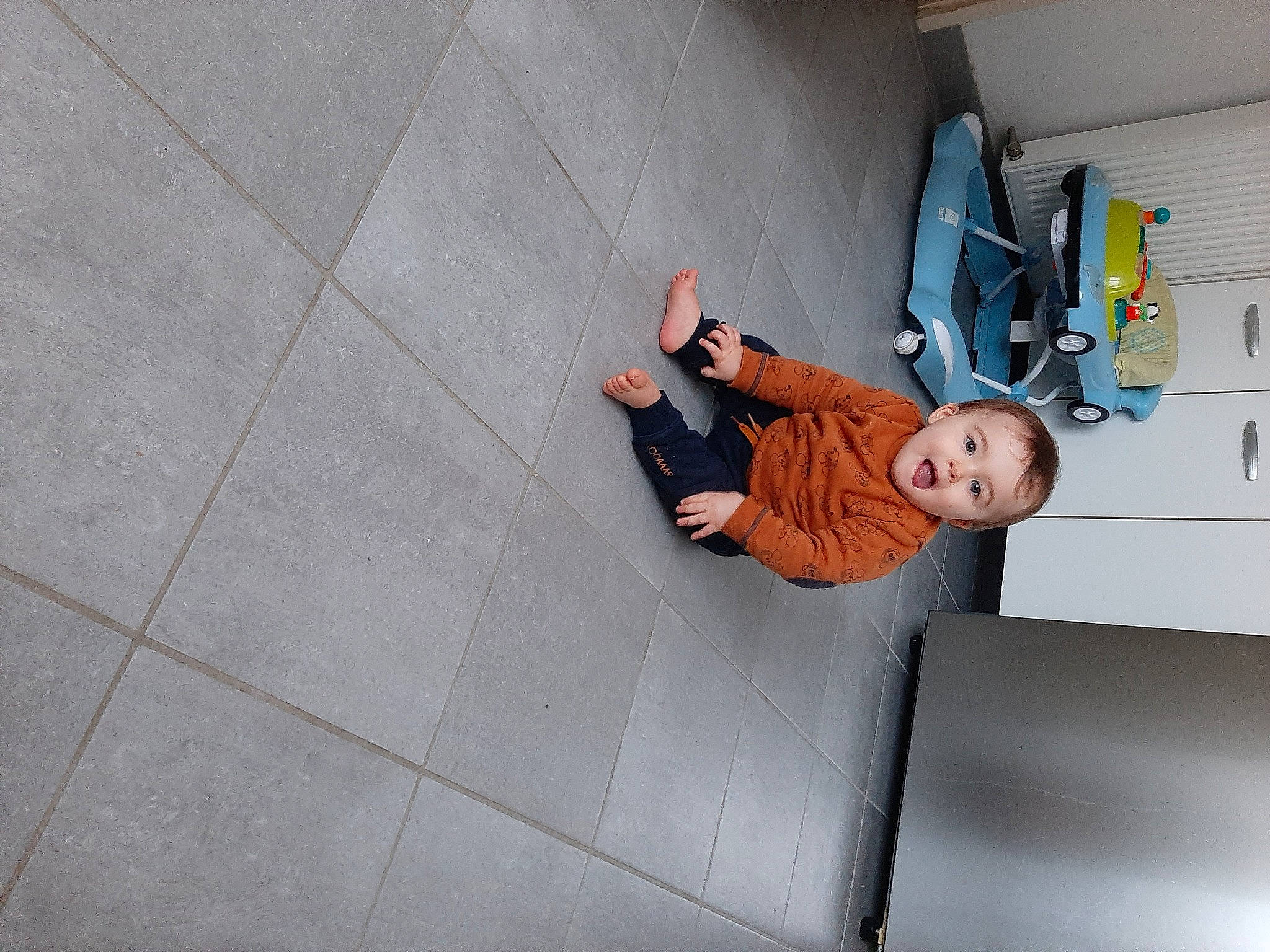 Lenny participe au concours pour gagner de l'argent avec cette photo : adventure, child, concrete, floor, flooring, fun, human_leg, machine, pattern, person, road_surface, room, sandal, sidewalk, sitting, stairs, surprise, t_shirt, tile, toddler