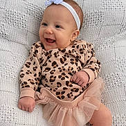 Zoey joined the competition — help win amazing prizes! baby, smiling, headband, flower, leopard_print, sweater, tutu_skirt, pink, white, knitted_blanket, texture, happy, infant, cute, portrait, child, person, apparel, cozy, indoor
