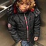 Andres joined the competition — help win amazing prizes! child, curly_hair, black_jacket, hood, jeans, sneakers, elevator, metal_wall, floor, standing, casual, winter_clothing, young, portrait, indoor, thoughtful, crossed_feet, fashion, person, alone
