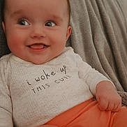 Brooklyn is registered to the contest to win money with this photo: baby, blanket, child, clothing, cozy, cute, expression, face, funny, hands, happy, indoor, infant, orange_pants, person, portrait, sitting, skin, smiling, white_top