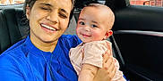 Ram is registered to the contest to win money with this photo: woman, baby, child, car_interior, blue_clothing, pink_clothing, smile, happy, portrait, holding, seat, window, urban_background, family, affection, person, casual, daylight, skin, hand