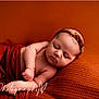Naomi is registered to the contest to win money with this photo: baby, newborn, infant, sleeping, headband, blanket, knit_blanket, orange, warm_tone, portrait, studio, peaceful, wrapped, chubby_cheeks, closed_eyes, arm, pillow, cute, soft_texture, watermark