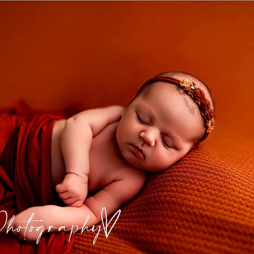 Naomi is registered to the contest to win money with this photo: arm, baby, blanket, chubby_cheeks, closed_eyes, cute, headband, infant, knit_blanket, newborn, orange, peaceful, pillow, portrait, sleeping, soft_texture, studio, warm_tone, watermark, wrapped