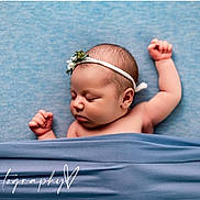 Naomi joined the competition — help win amazing prizes! baby, newborn, infant, sleeping, headband, blanket, blue_background, portrait, cute, peaceful, skin, arm, hand, closed_eyes, lying_down, studio_photography, soft_lighting, tucked_in, photography_watermark, adorable