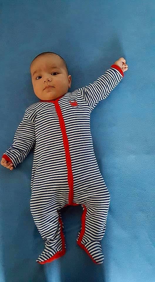 Patrick participe au concours pour gagner de l'argent avec cette photo : arm, azure, baby, baby_toddler_clothing, facial_expression, finger, gesture, hand, happy, head, human_body, joint, outerwear, pattern, person, sleeve, standing, t_shirt, textile, thumb