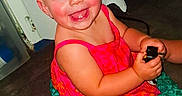 Nova is registered to the contest to win money with this photo: child, toddler, smiling, blue_eyes, dress, colorful_clothing, sitting, floor, indoor, plug, happy, cute, person, skin, face, short_hair, baby, holding_object, cheerful, rosy_cheeks