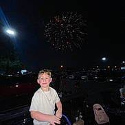 Matthew joined the competition — help win amazing prizes! child, boy, fireworks, night, parking_lot, car, people, celebration, flash, smile, clothing, chain_necklace, dark_sky, outdoor, festive, illumination, urban, excited, standing, event