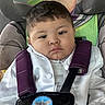 toddler, child, car_seat, safety_harness, white_jacket, purple_straps, buzz_lightyear, toy_story, seat_cover, young_child, portrait, indoors, serious_expression, baby, cute, seatbelt, car_interior, closeup, face, person