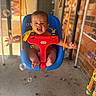 baby, swing, child, blue_swing, red_safety_bar, bubbles, happy, outdoor, porch, brick_wall, playful, infant, toy, yellow_straps, feet, hands, smile, expression, sunlight, concrete_floor