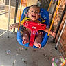 Ronan is registered to the contest to win money with this photo: baby, swing, bubbles, blue_seat, orange_ropes, outdoor, happy, smiling, child, playtime, feet, hands, concrete_floor, brick_wall, door, sunlight, shadow, toy, infant, joy