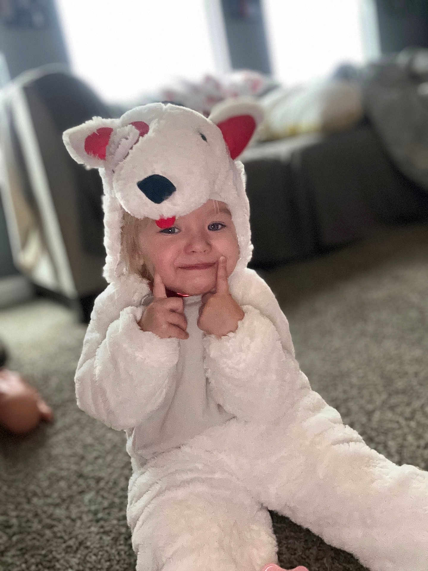 Raelynn joined the competition — help win amazing prizes! toddler, child, costume, animal_costume, white, fluffy, indoors, carpet, smiling, cute, playful, hood, ears, nose, face, person, sitting, living_room, blurred_background, happy