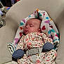 baby, infant, sleeping, blanket, heart_pattern, onesie, floral_print, mittens, striped_mittens, harness, buckle, baby_seat, bouncer, cozy, soft, indoor, newborn, cute, peaceful, fan_in_background