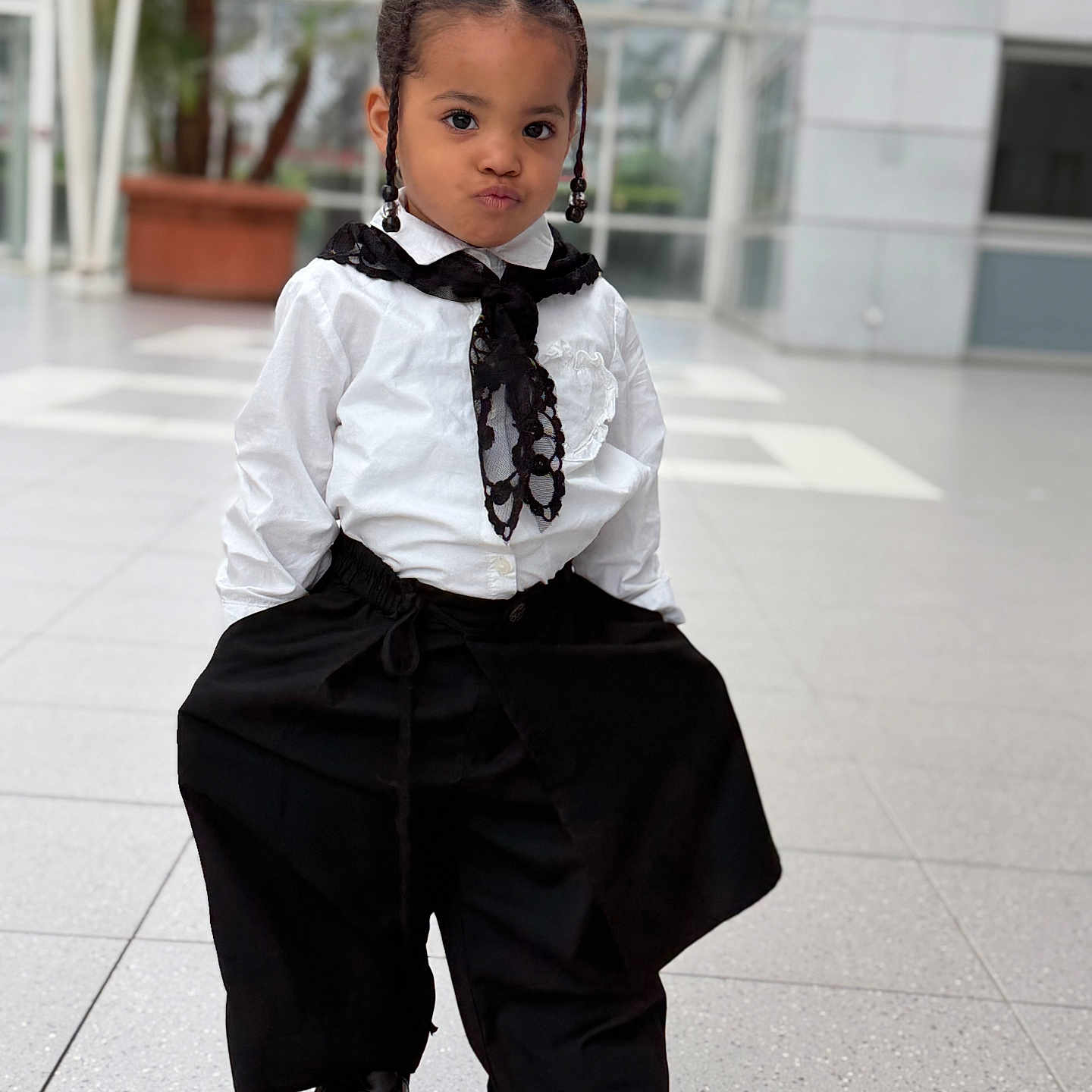 Nélya a rejoint le concours — aidez-le/la à gagner de superbes lots ! child, portrait, fashion, braids, black_and_white, indoor, potted_plant, modern, confident, stylish, pants, shirt, lace, shoes, floor, window, glass, pose, expression, cute