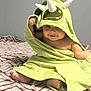 baby, child, towel, green, dinosaur, horns, smile, cute, blanket, indoor, soft, feet, hand, face, playful, cozy, infant, happy, wrapped, sitting