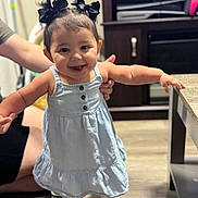 Mila Raine joined the competition — help win amazing prizes! baby, black_hair, child, cute, dress, floor, furniture, hair_bows, happy, home, indoor, person, portrait, smile, sneakers, standing, supporting_hand, table, toddler, young_child