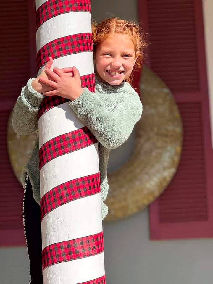 Alayah is registered to the contest to win money with this photo: cap, costume_hat, event, fashion_accessory, fur, fur_clothing, gesture, happy, headgear, joy, outerwear, person, red, shawl, shoulder, sleeve, smile, standing, textile, toddler