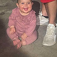 Remi joined the competition — help win amazing prizes! baby, child, smiling, pink_clothing, sitting, barefoot, concrete_floor, adult_legs, white_sneakers, shorts, happy, indoor, casual, cute, infant, person, portrait, playful, young_child, footwear
