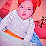 baby, child, headband, orange, white_clothing, basket, blanket, blue_blanket, pillow, decor, indoor, portrait, face, cute, sitting, cozy, soft, infant, young_child, warm_lighting