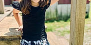 Kinlee Raye joined the competition — help win amazing prizes! black_top, bow, building, casual, child, daylight, girl, grass, happy, leaning, nature, outdoor, patterned_shorts, person, portrait, smiling, summer, sunlight, wood, wooden_stairs