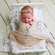 Eloisa is registered to the contest to win money with this photo: newborn, baby, swaddle, headband, flower_crown, sleeping, bed, white_bed, lace_blanket, wooden_floor, infant, cute, peaceful, portrait, resting, soft_texture, wrapped, small_bed, delicate, cozy