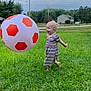 barefoot, child, cloudy, daytime, fun, grass, greenery, happy, house, inflatable_ball, nature, outdoor, person, play, sky, smiling, soccer_ball, striped_dress, toddler, trees