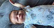 Colt is registered to the contest to win money with this photo: arm, baby, blanket, cartoon_print, child, clothing, cozy, eyes_open, face, gray_blanket, hair, hand, indoor, infant, lying_down, newborn, onesie, photography, portrait, stitch_character