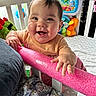 baby, child, crib, toy, smile, happy, indoor, infant, colorful, foam_bar, person, young_child, play, cute, furniture, clothing, face, hand, bed, expression
