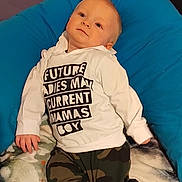 Jaxon is registered to the contest to win money with this photo: baby, blanket, camo_pants, casual, child, clothing, comfortable, curious, cushion, cute, face, hoodie, indoor, infant, lying_down, person, portrait, relaxed, socks, young_child