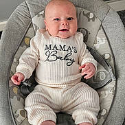 Jace is registered to the contest to win money with this photo: baby, infant, smiling, clothing, ribbed_outfit, baby_rocker, elephant_pattern, cushion, comfort, indoor, happy, cute, child, person, footwear_none, face, small_hands, soft_toys_pattern, seated, home