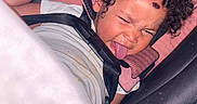 Harmonie is registered to the contest to win money with this photo: child, toddler, car_seat, curly_hair, tongue_out, playful, straps, seatbelt, white_shirt, indoors, cute, funny_face, person, baby, seat, car, expression, young_child, hair, sitting