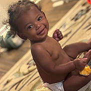 Devonie joined the competition — help win amazing prizes! baby, child, diaper, smile, indoor, carpet, snack, curly_hair, plush_toy, happy, toddler, person, cute, sitting, home, floor, infant, playful, bright_eyes, young