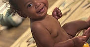 Devonie joined the competition — help win amazing prizes! baby, child, smiling, diaper, indoor, carpet, toy, food, happy, cute, person, toddler, skin, face, hand, sitting, home, living_room, curly_hair, playful