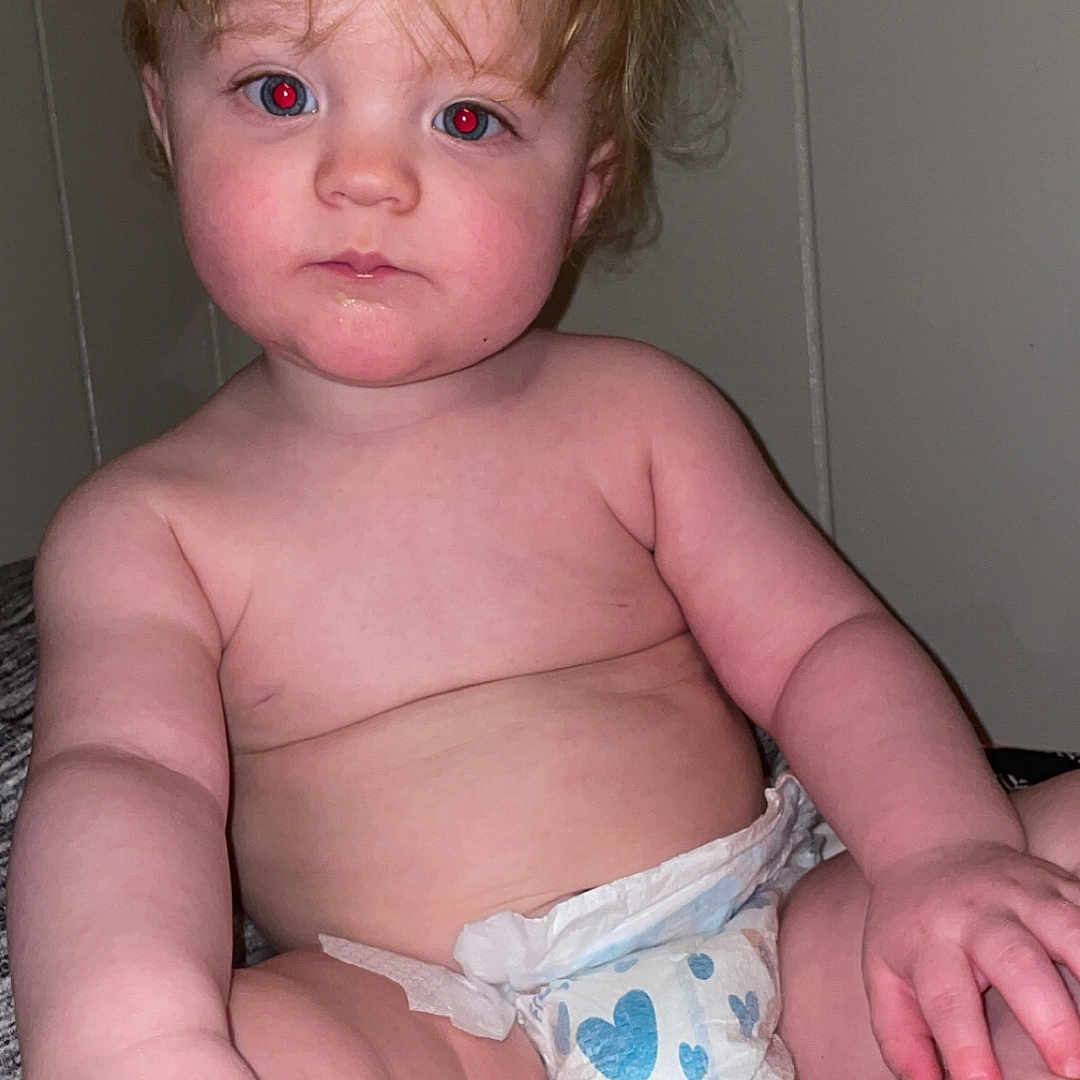 Kody is registered to the contest to win money with this photo: baby, blanket, blond_hair, child, curly_hair, cute, diaper, expressionless, face, foot, hand, indoor, infant, person, plump, portrait, red_eye, sitting, skin, young_child