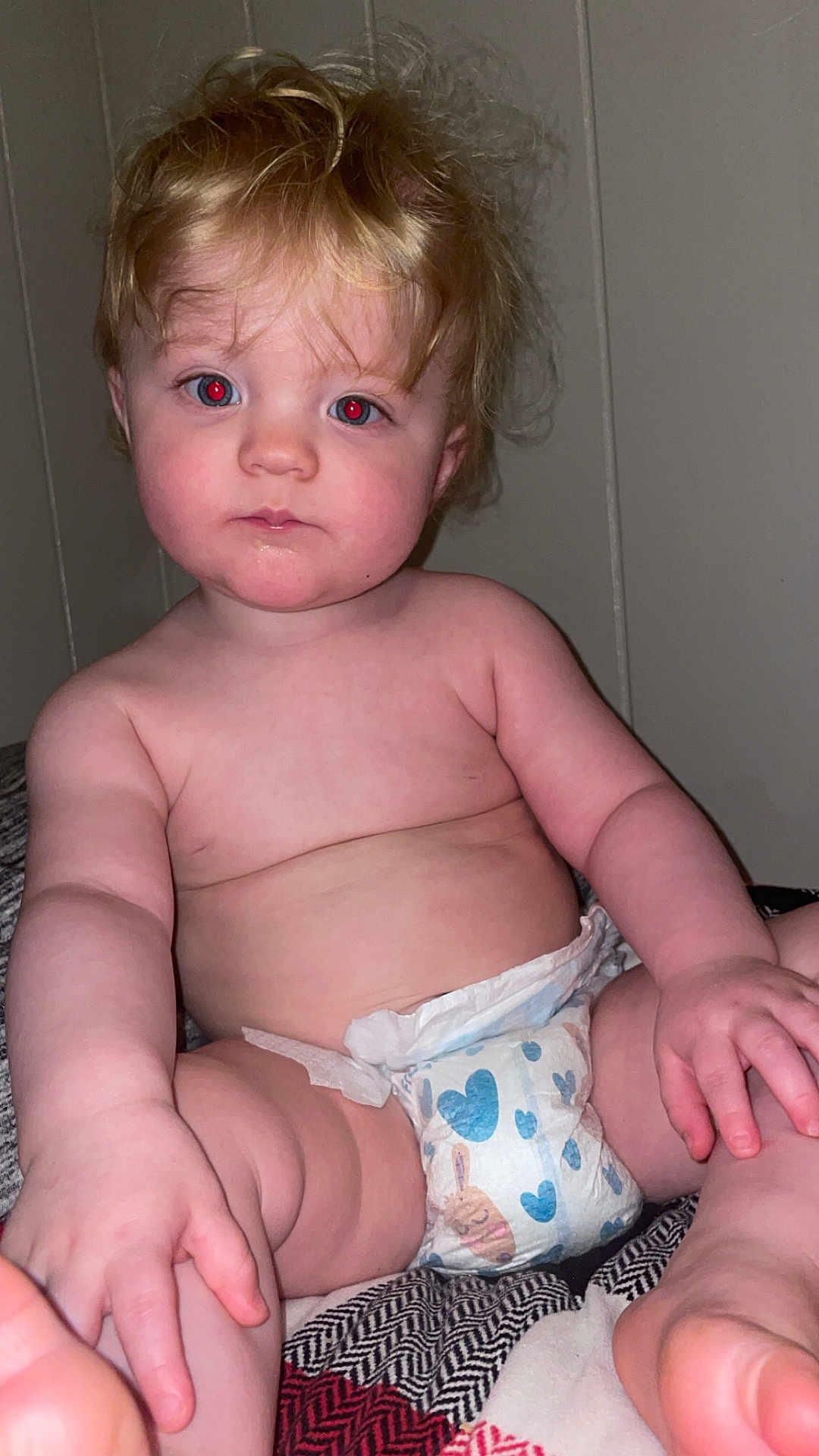 Kody is registered to the contest to win money with this photo: baby, child, diaper, blond_hair, red_eye, skin, hand, foot, sitting, indoor, blanket, curly_hair, infant, cute, face, expressionless, plump, person, portrait, young_child