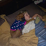 Daisy is registered to the contest to win money with this photo: bed, blanket, child, clothing, dog, dog_clothing, furniture, hair, head, indoor, night, pajamas, pet, pillow, sleeping, sleepwear, toddler, toy, warm, young