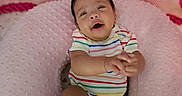 Kaveri is registered to the contest to win money with this photo: baby, baby_bed, barefoot, child, close_up, colorful_clothing, cozy, hands, happy, indoor, infant, lying_down, nursery, photography, pillow, pink_blanket, portrait, smiling, soft_blanket, striped_onesie