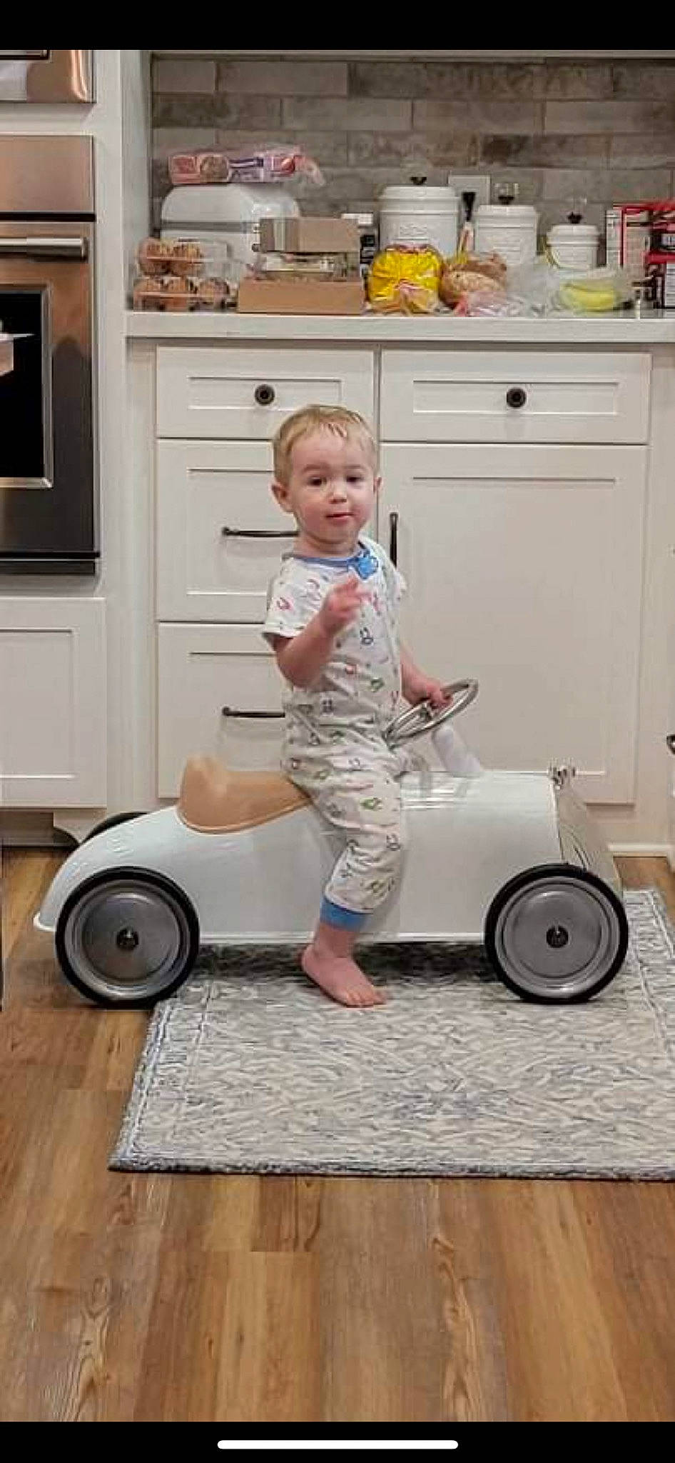 Axl is registered to the contest to win money with this photo: automotive_design, automotive_tire, cabinetry, countertop, drawer, floor, flooring, home_appliance, joint, kitchen, kitchen_appliance, major_appliance, person, product, riding_toy, shorts, shoulder, standing, tire, vehicle